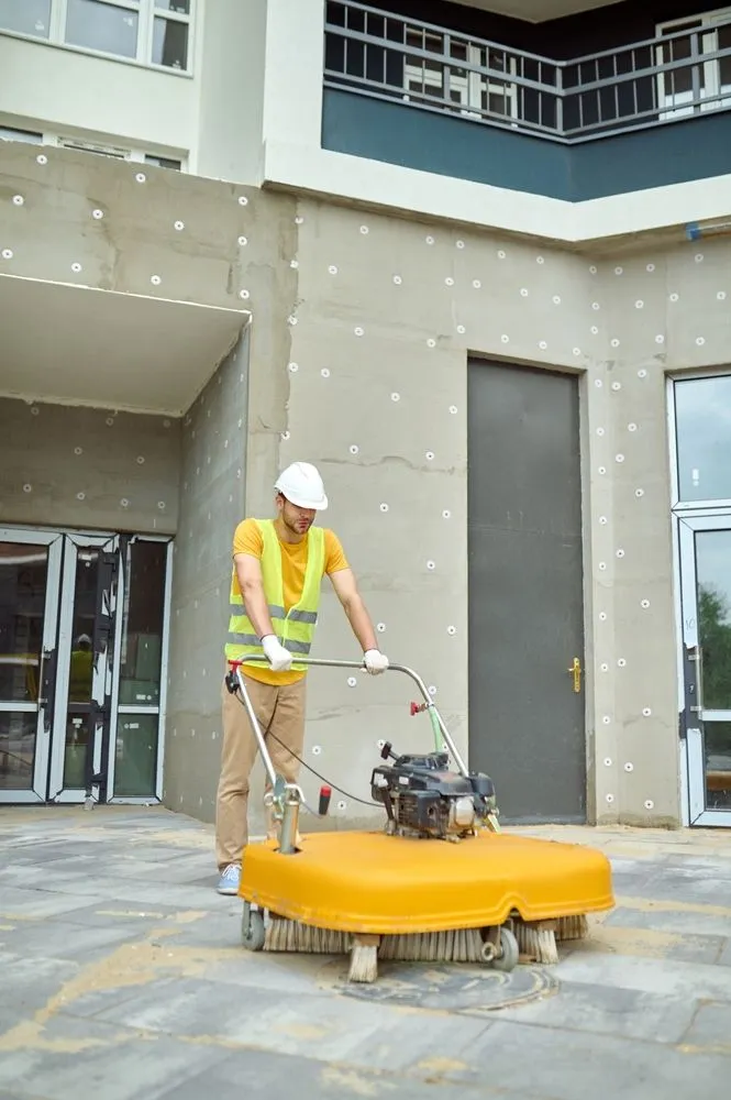 A worker sweeping a walkway outside a new building