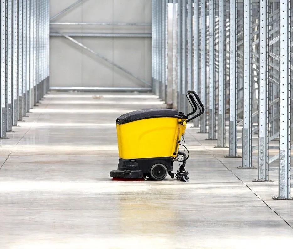 A floor scrubber on a polished warehouse floor