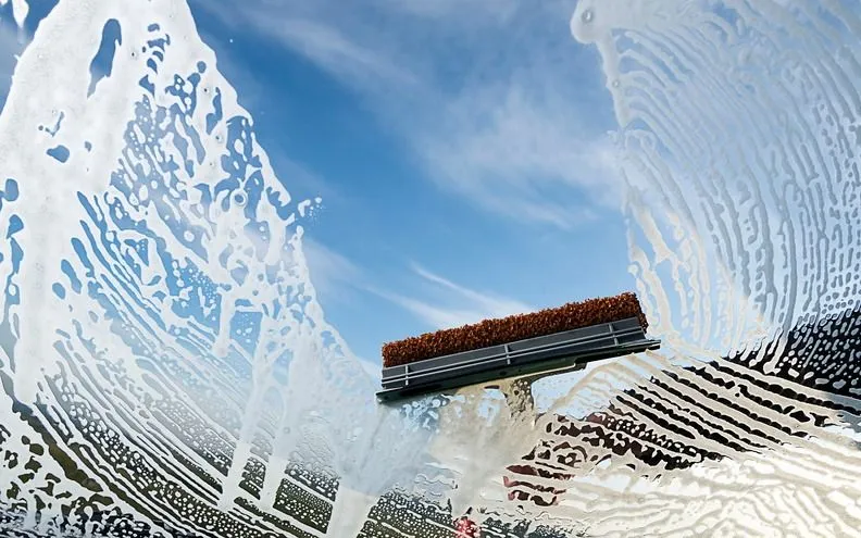A squeegee clearing soap from a pane of glass